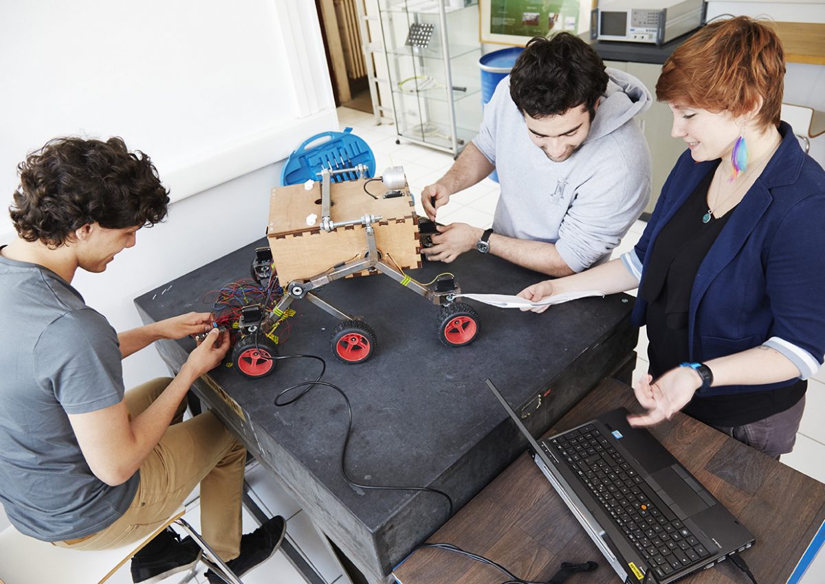 Trois étudiants de Supméca travaillent sur un robot mécanique à six roues