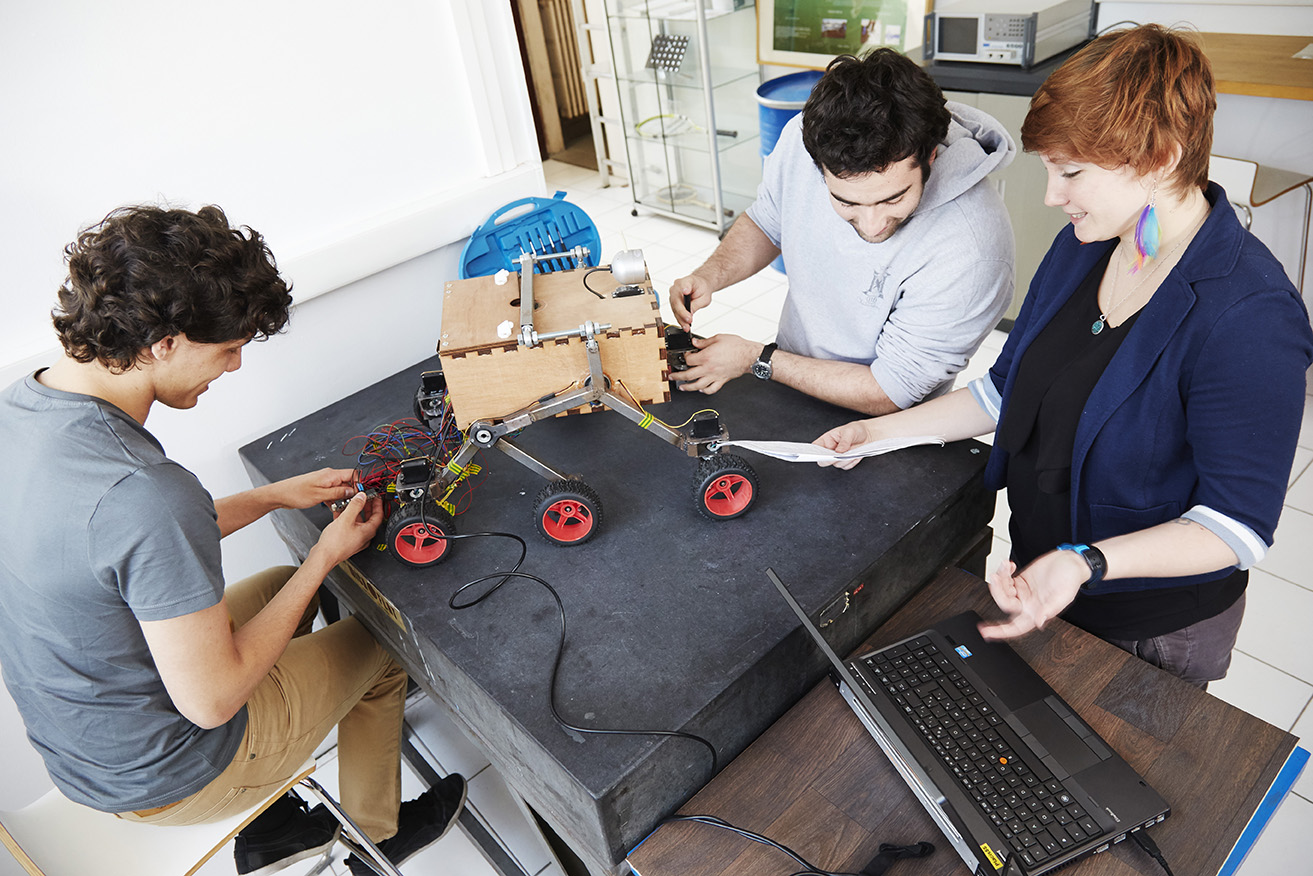 Trois étudiants de Supméca travaillent sur un robot mécanique à six roues