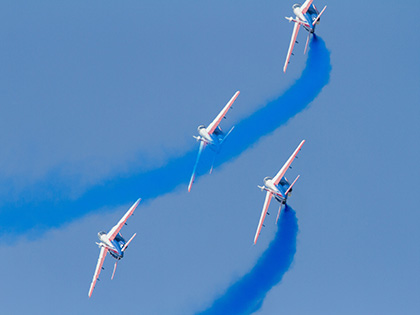 4 avions survolant le ciel avec une trainée de fumée bleue