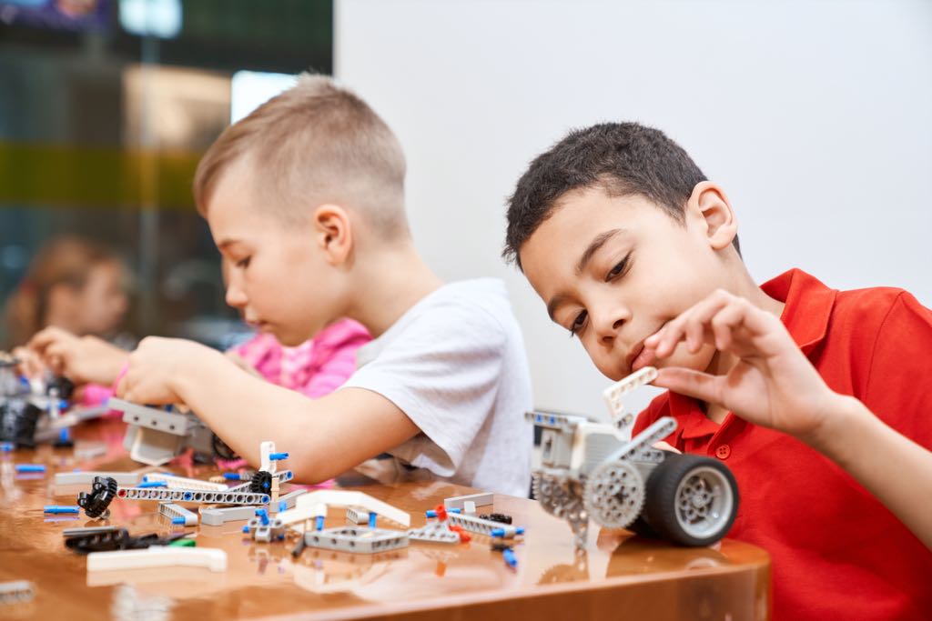 Deux enfants jouent et fabriquent des voitures.