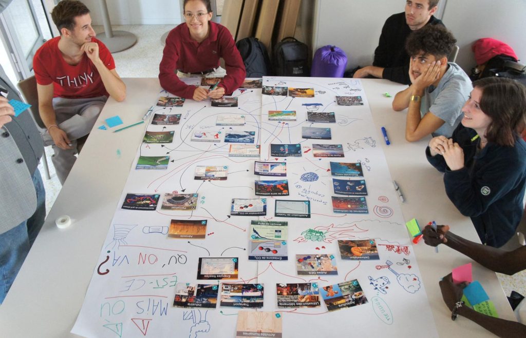Étudiants et étudiantes autour d'une table en train de composer une fresque du climat